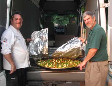 Emilio Gervilla and volunteer Mike Bradt bring in the paella